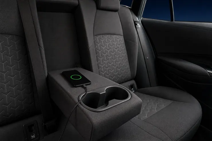 A phone charging on the rear armrest